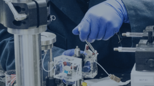 gloved hands using a wrench to put together lab equipment