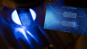 a microfluidic device is shown over a lighted microscope